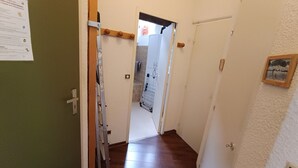 A hallway with wooden flooring, a door with a coat rack, and a wall-mounted sign. - Lovely 2P 5 Pers Ski-in Ski-out Top Floor Pets Welcome (Montgenèvre)