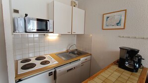 A compact kitchen with white cabinets, a microwave, a stove, a dishwasher, and a coffee maker. - Ski-in/out apartment for 6, pet friendly, slope views (Montgenèvre)