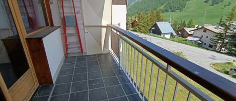 A balcony with a tiled floor, a red ladder, and a railing.