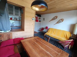 A cozy room with a wooden table, a sofa, and a yellow-covered couch.