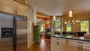 Eine moderne Küche mit Holzausstattung, einem Edelstahlkühlschrank und einer großen Kochinsel mit integriertem Spülbecken.