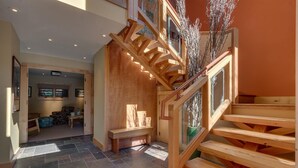 Eine Holztreppe mit Glastrennwand, die zu einer zweiten Etage führt.