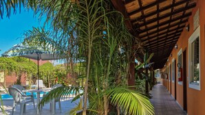 A covered outdoor area with a pool, lounge chairs, and palm trees. - Pousada Quatro Estações Paraty (Paraty)