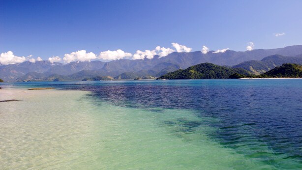 A coastal landscape with clear waters, a sandy beach, and lush green hills in the background. - Pousada Quatro Estações Paraty (Paraty)