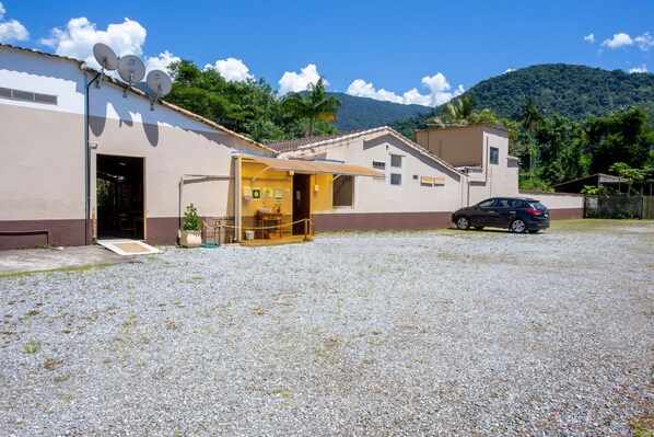 A building with a gravel driveway, a car parked in front, and a mountain in the background. - Pousada Quatro Estações Paraty (Paraty)