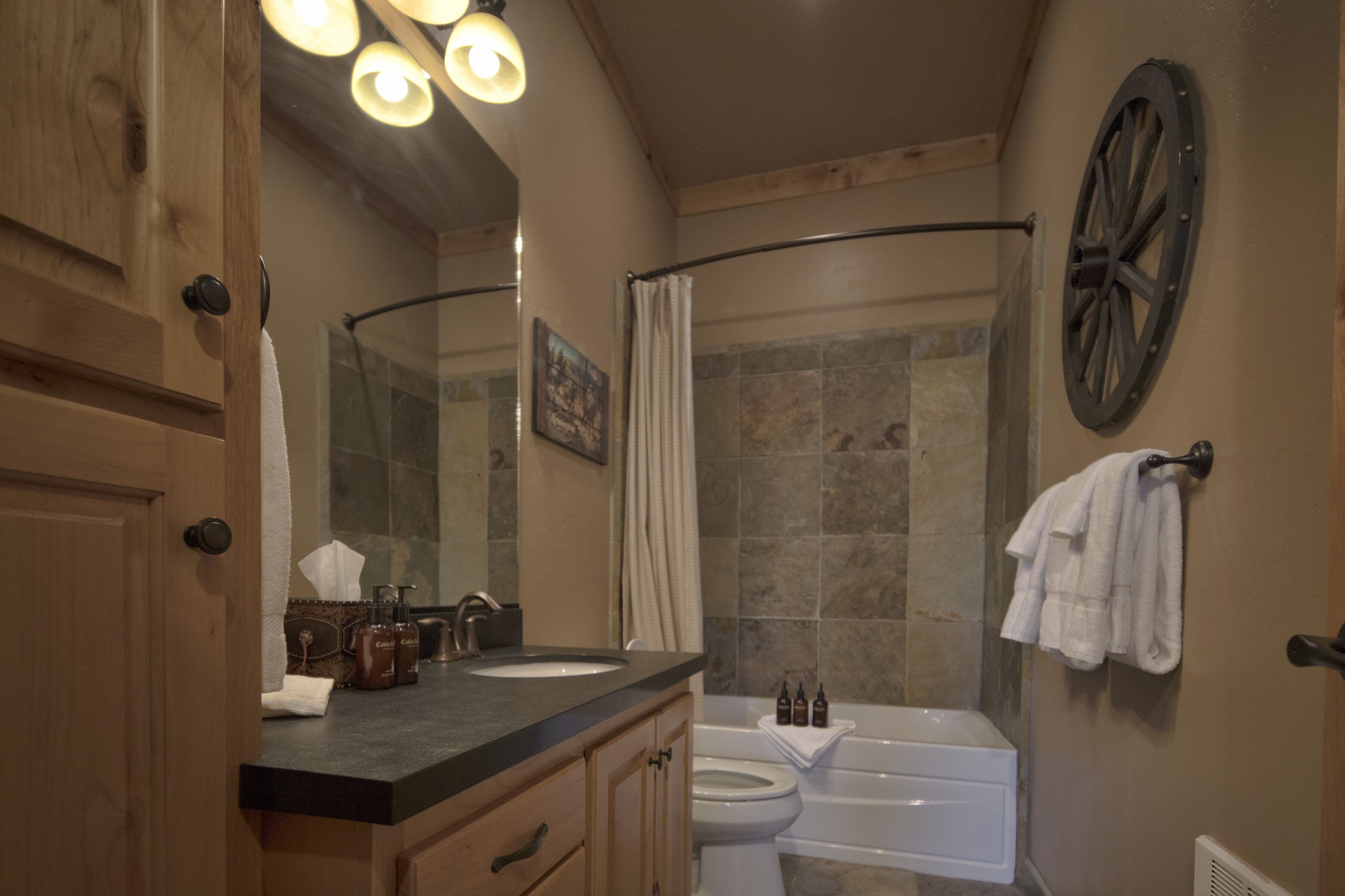 Un baño con un tocador de madera, un lavamanos, un inodoro y una bañera.