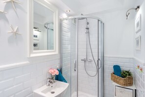 A modern bathroom with a glass-enclosed shower, a white sink, and decorative starfish on the wall. - Elite Apartments Center Grobla (Gdansk)