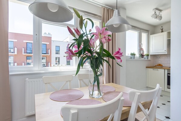 Enjoy meals in this dining area with a table for four, a glass vase, and a view of the urban landscape.
