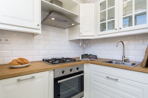 Enjoy cooking in this kitchen with a stainless steel gas stove, oven, and glass-fronted cabinets.
