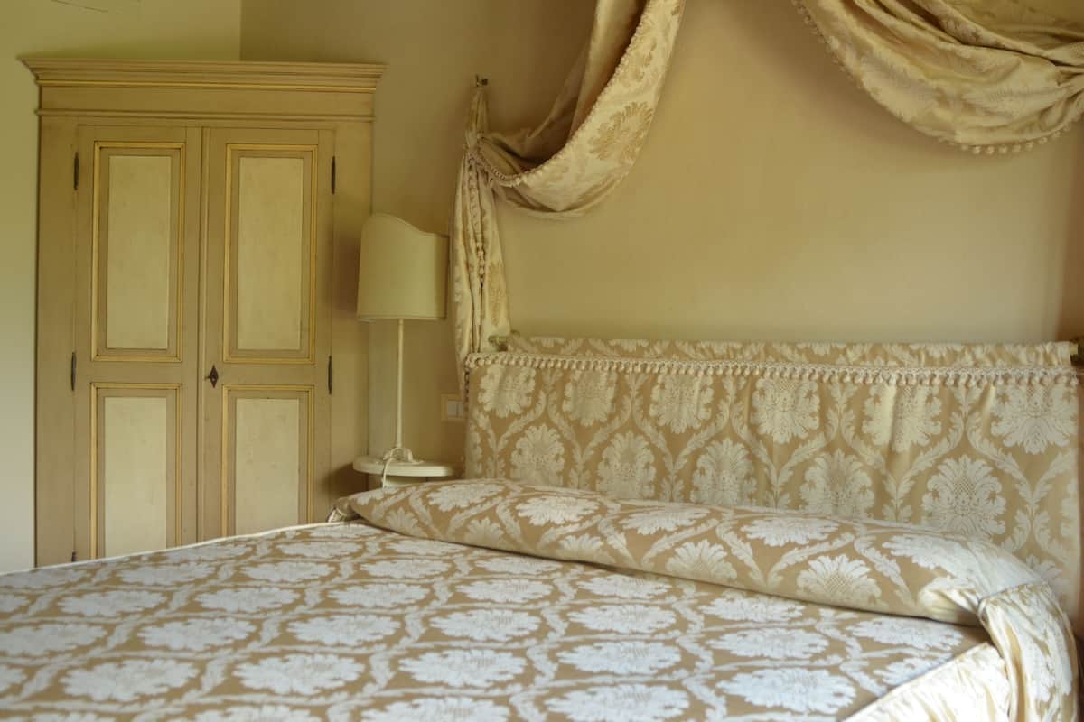 A bedroom with a bed, a nightstand, a lamp, and a wardrobe.