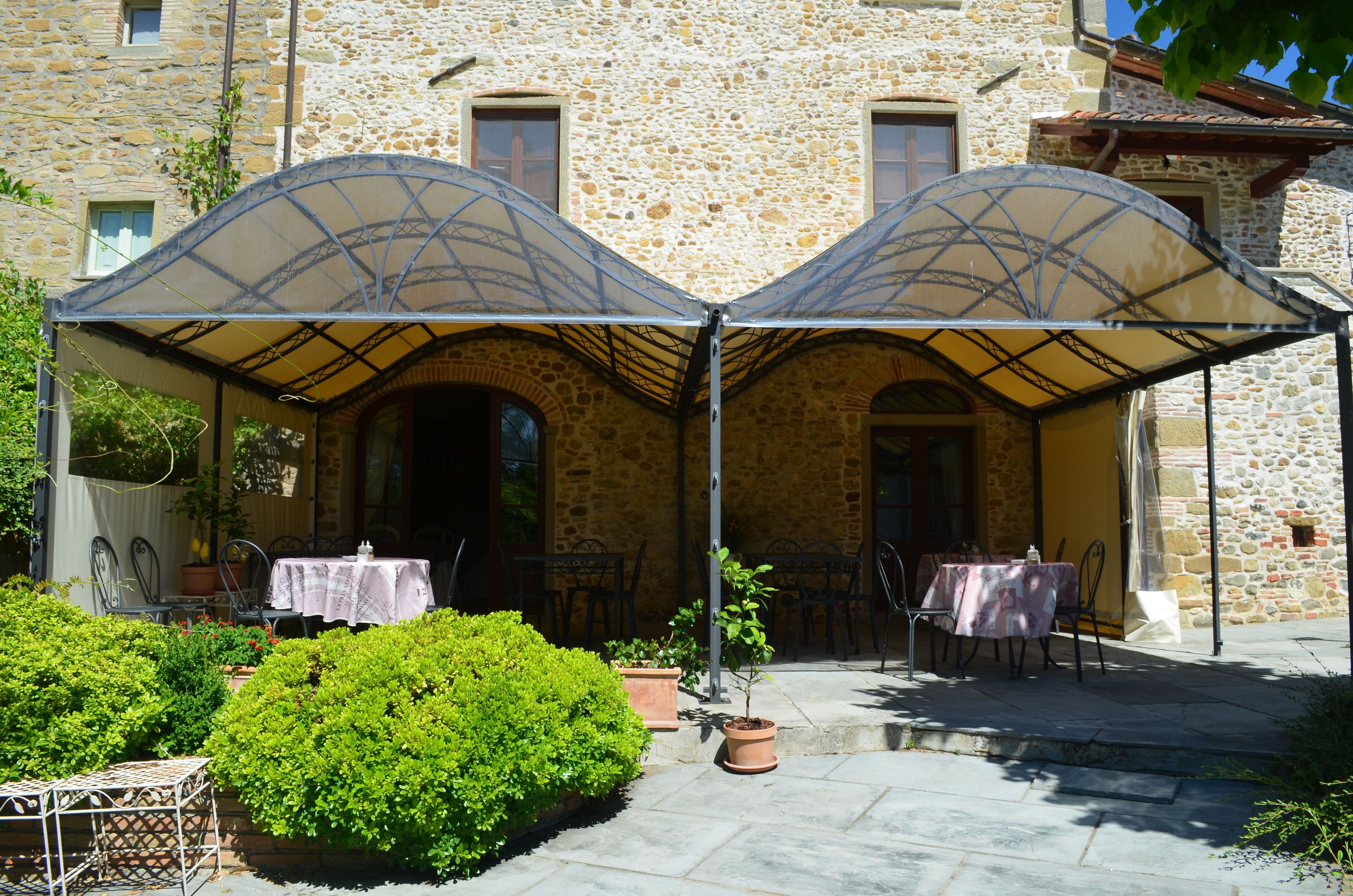 A stone building with a covered outdoor seating area, tables, and chairs.