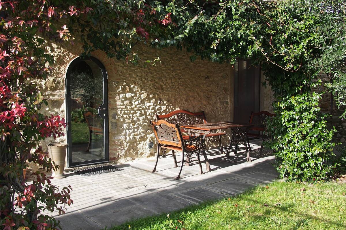A stone building with a wooden table and chairs outside.