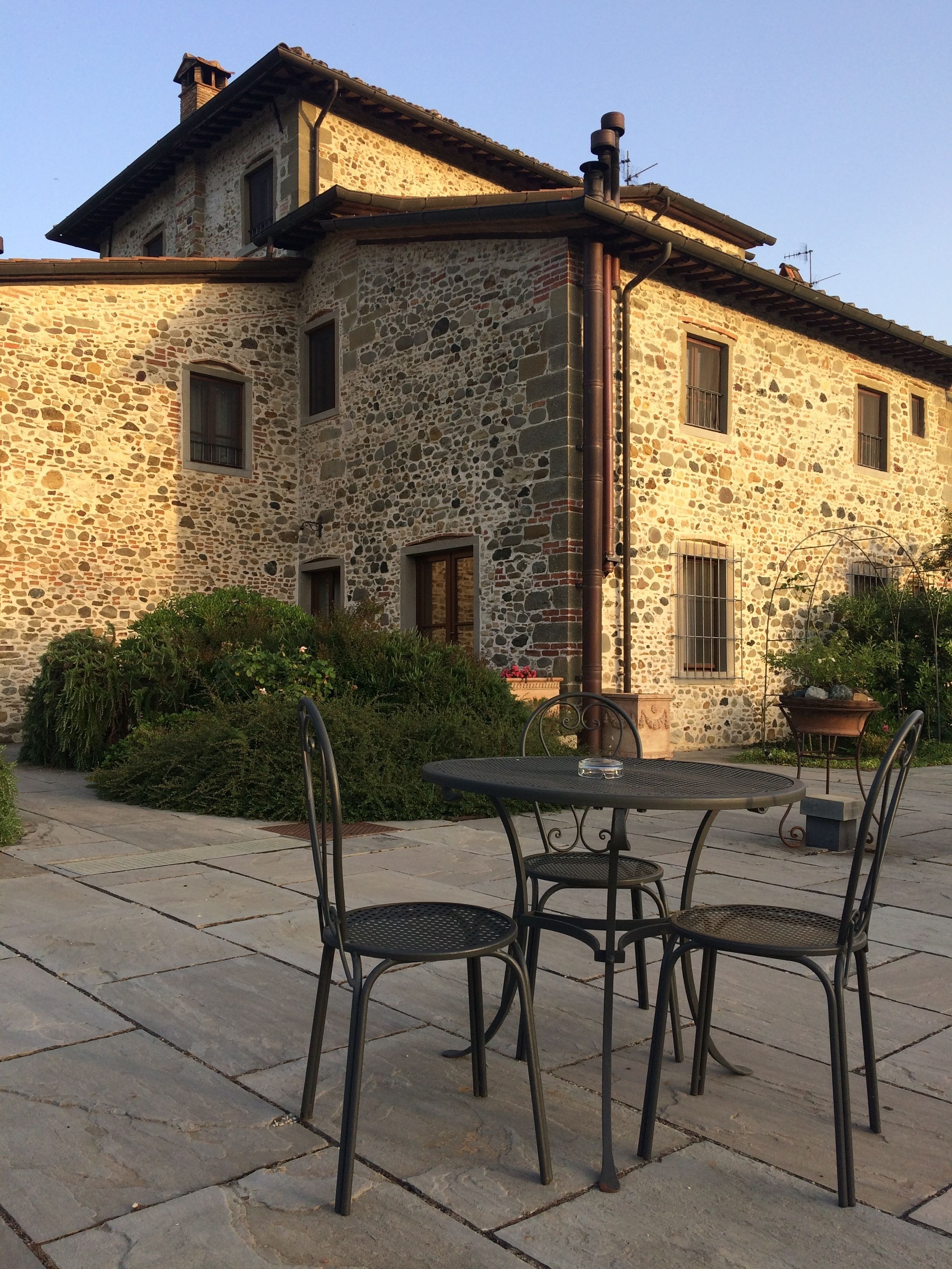 A stone building with a patio area featuring a round table and metal chairs.