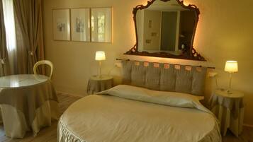 A neatly arranged bedroom with a large bed, two bedside tables with lamps, a round table, and a chair.