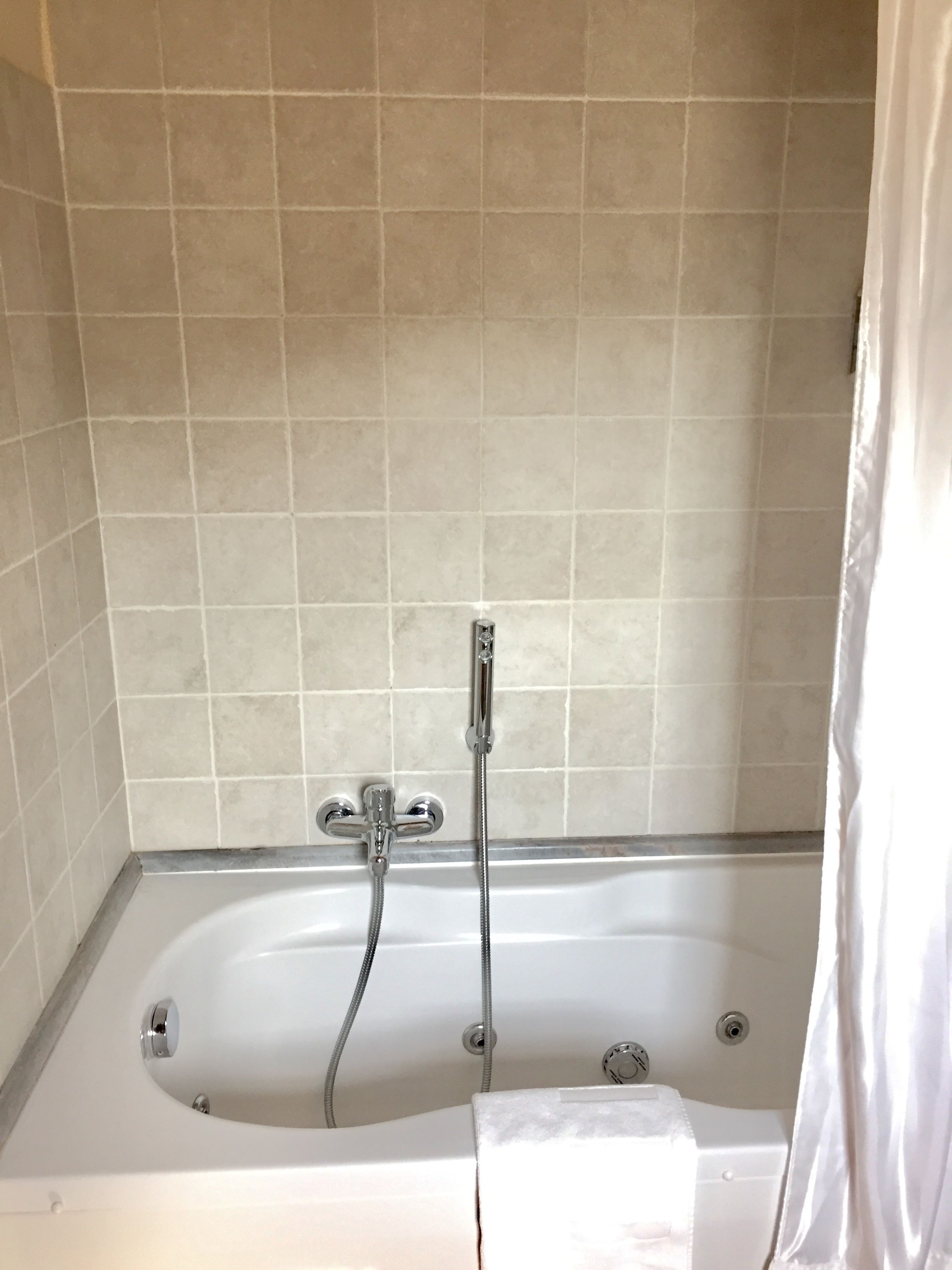A bathroom with a bathtub, a showerhead, and a curtain.