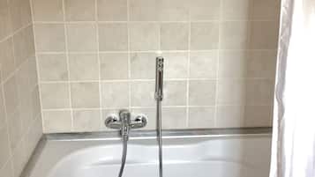 A bathroom with a bathtub, a showerhead, and a curtain.
