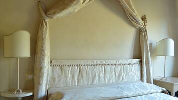A bedroom with a canopy bed, bedside lamps, and a bedside table.