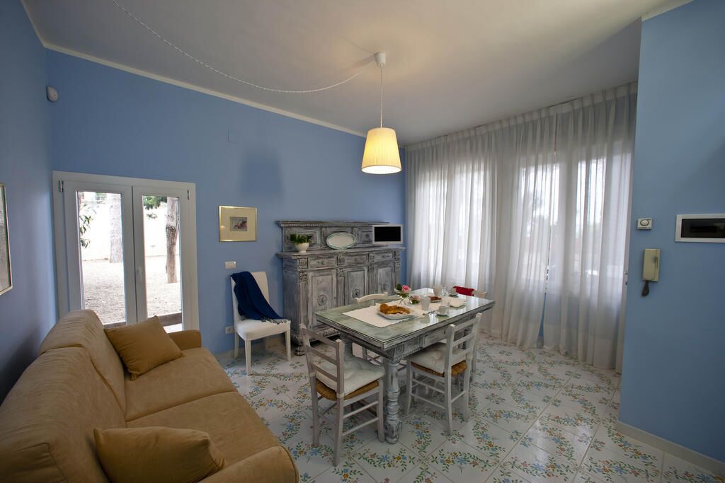 Een woonkamer met een bank, eettafel, stoelen en een open haard.