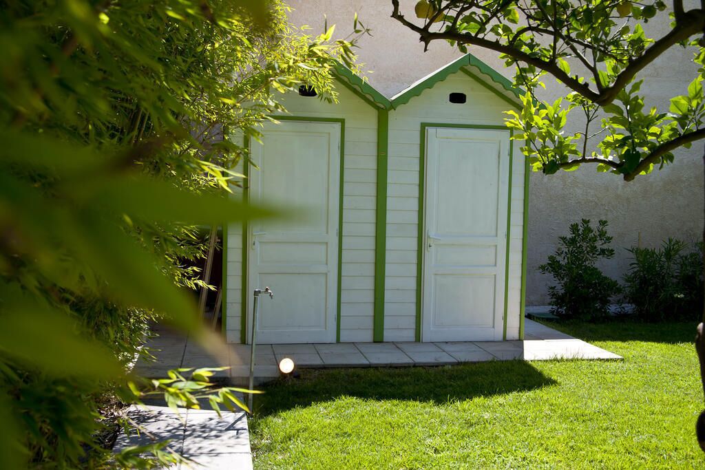 Garagem para dois carros com detalhes em verde, uma pequena árvore em primeiro plano e um gramado bem cuidado.