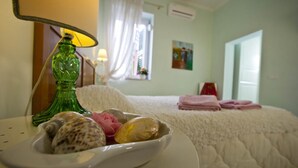 A hotel room with a bed, a bedside lamp, a window with curtains, and a painting on the wall. - La Villa della Meda (Taranto)