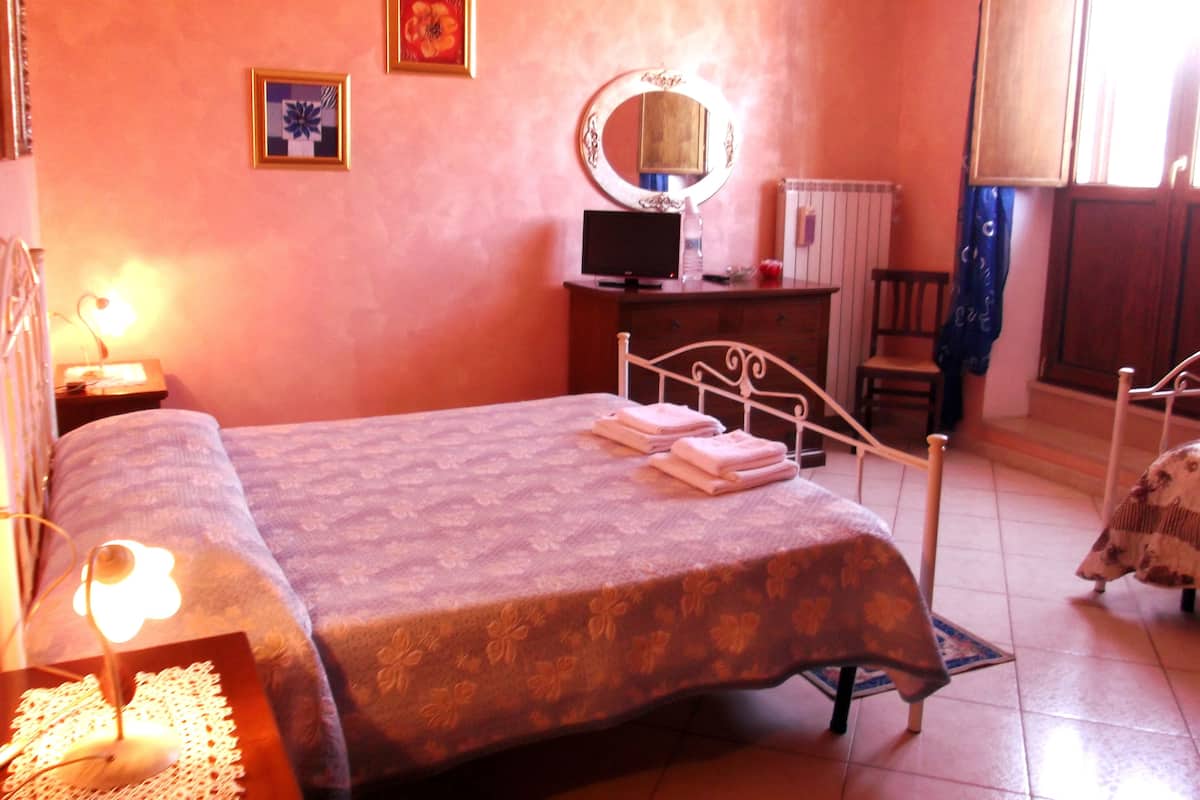 Une chambre à coucher comprenant un lit, une table de chevet, un miroir, une commode et une chaise.
