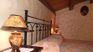 A bedroom with a wooden headboard, a bedside table with a lamp, and a floral bedspread. - Dolcedorme B&B (Terranova di Pollino)