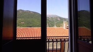 A view from a window with a tiled roof, overlooking a green hillside with a wind turbine. - Dolcedorme B&B (Terranova di Pollino)