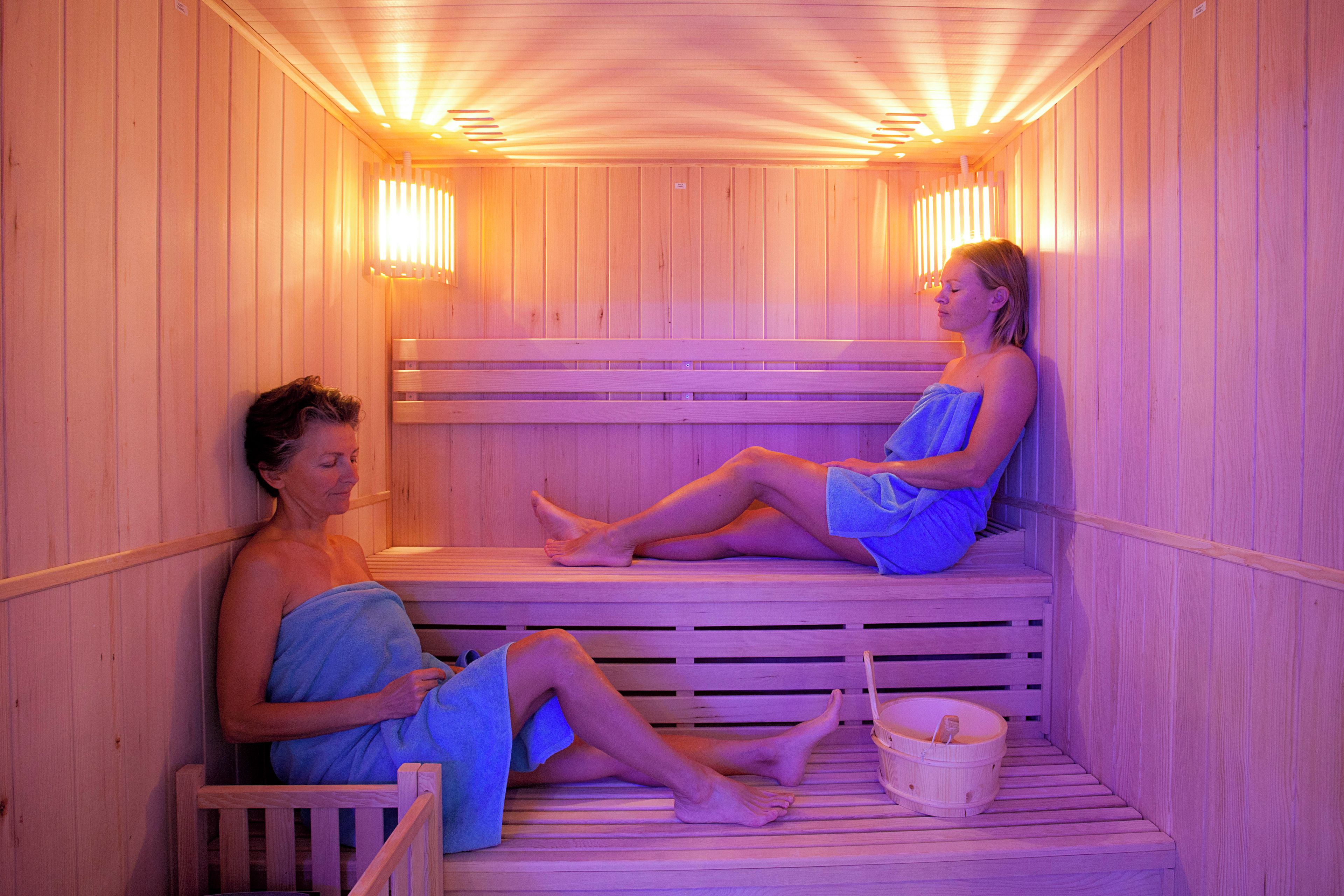 A sauna with wooden benches and benches, a wooden floor, and a small wooden bucket.