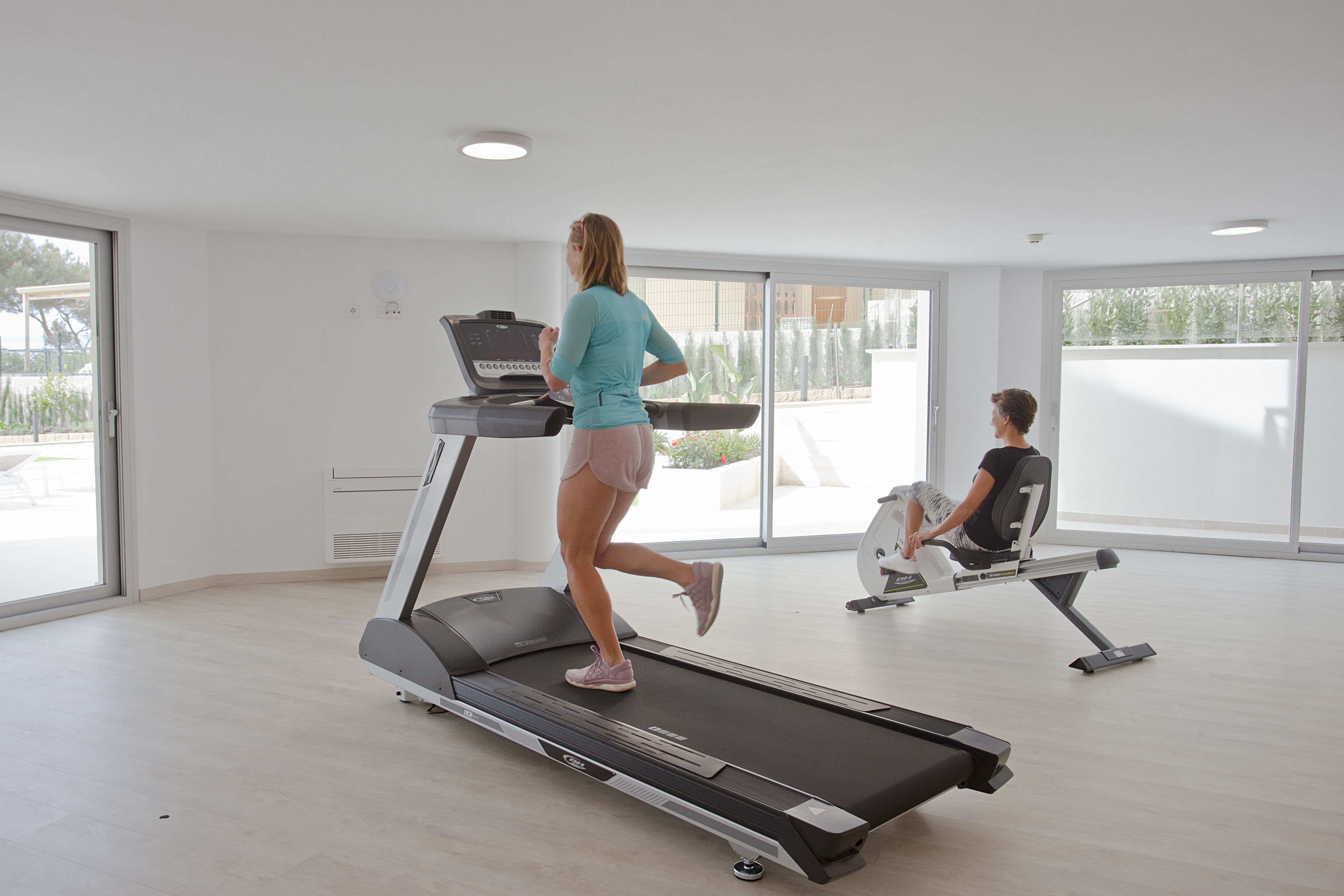 Ein geräumiges Fitnessstudio mit Laufband und Rudergerät.