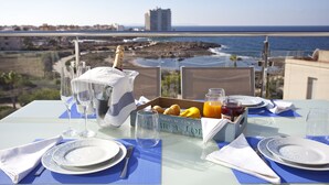 Una mesa lista para el desayuno con vista al océano y al paisaje urbano.