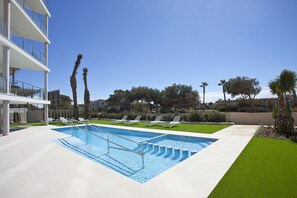 Una piscina al aire libre de temporada, sombrillas