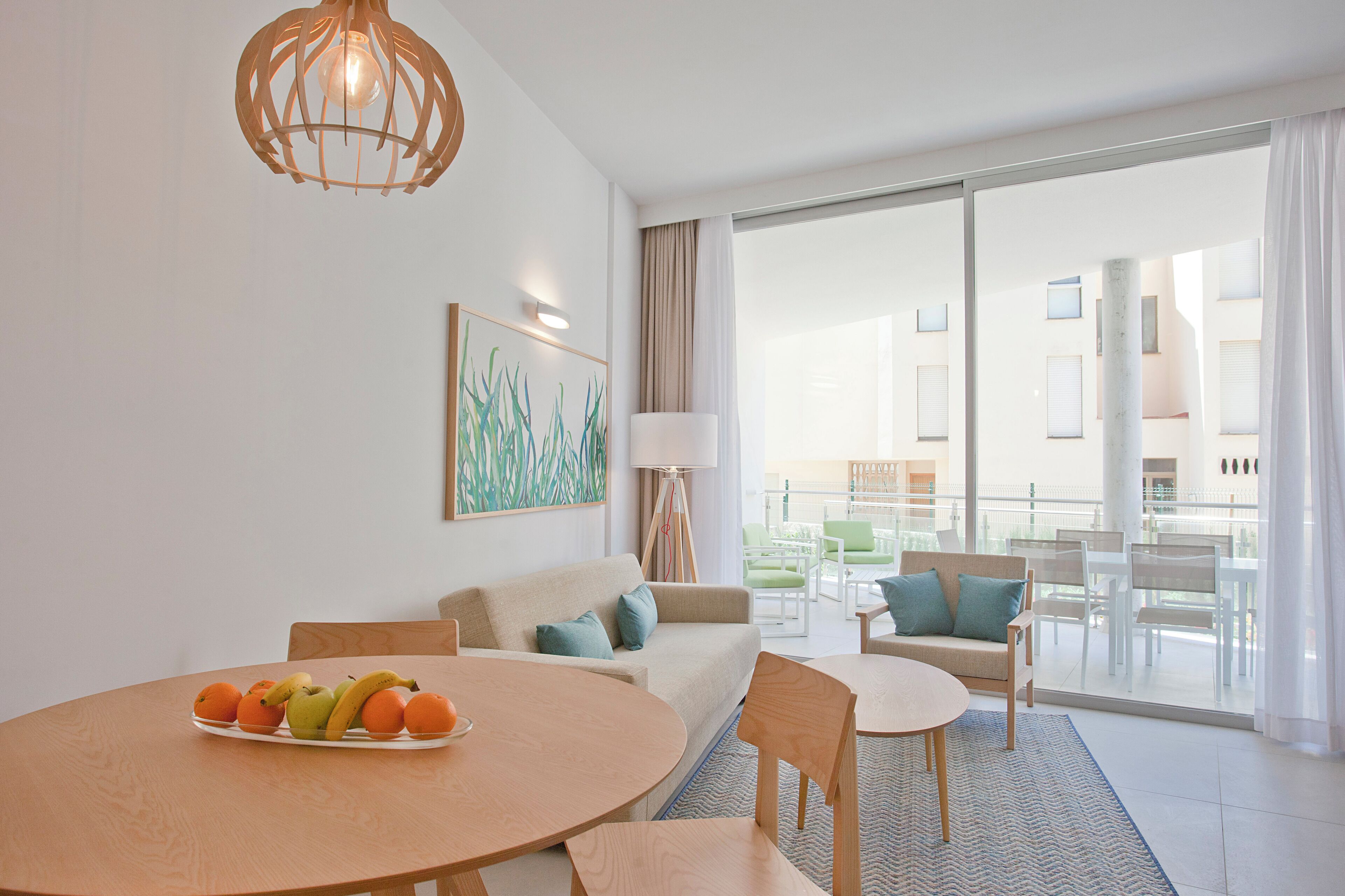 Un salon moderne avec une table ronde, un canapé et un balcon aménagé avec du mobilier d’extérieur.