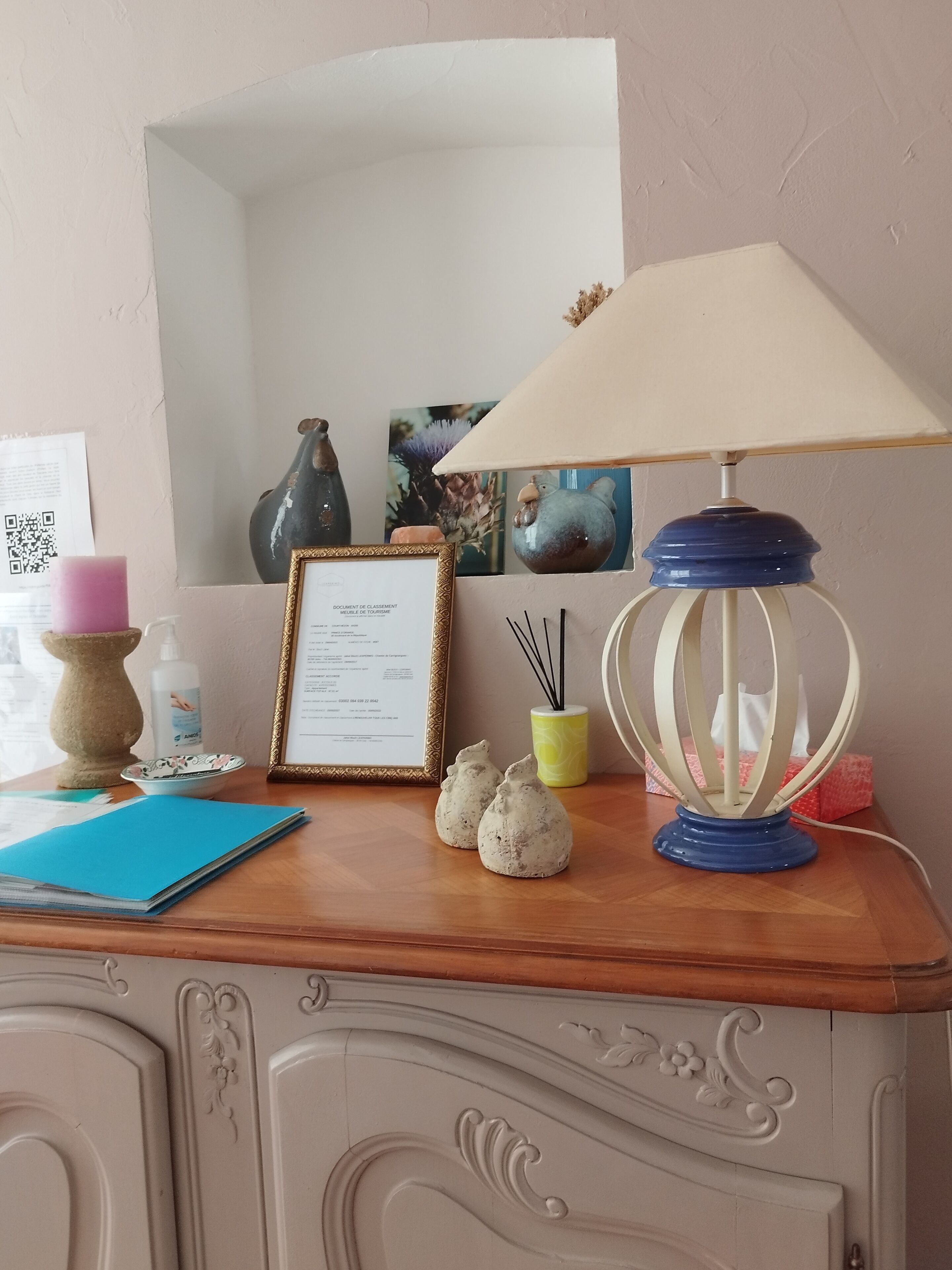 A wooden desk with a framed document, a blue folder, decorative items, and a lamp.