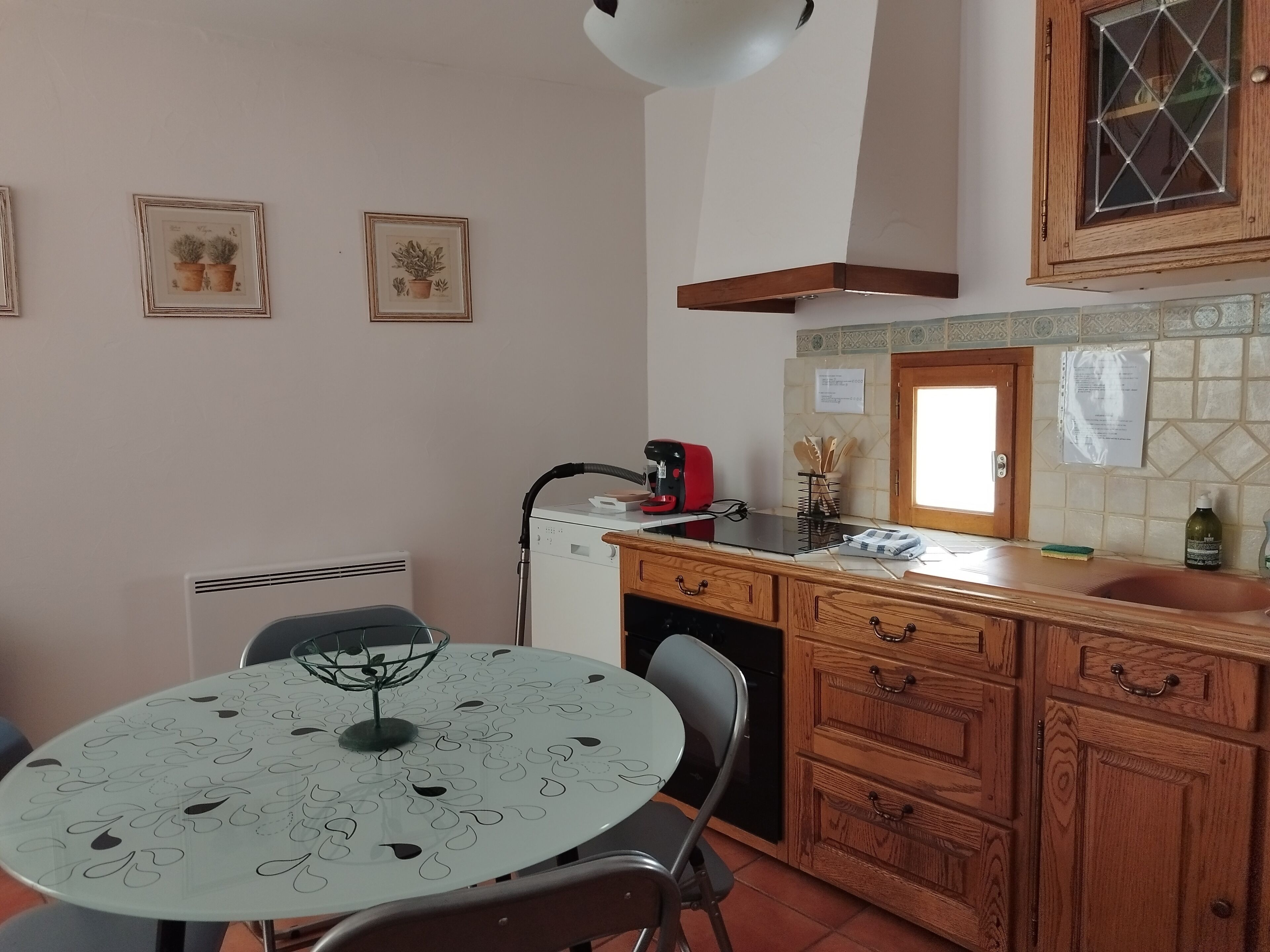 A compact kitchen with a round table, wooden cabinets, and a built-in oven.