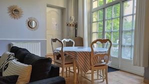 A dining area with a table and chairs, a radiator, decorative wall mirrors, and a window with blinds.