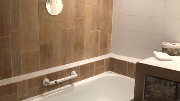Un baño moderno con una bañera independiente, un perchero para toallas y un inodoro.