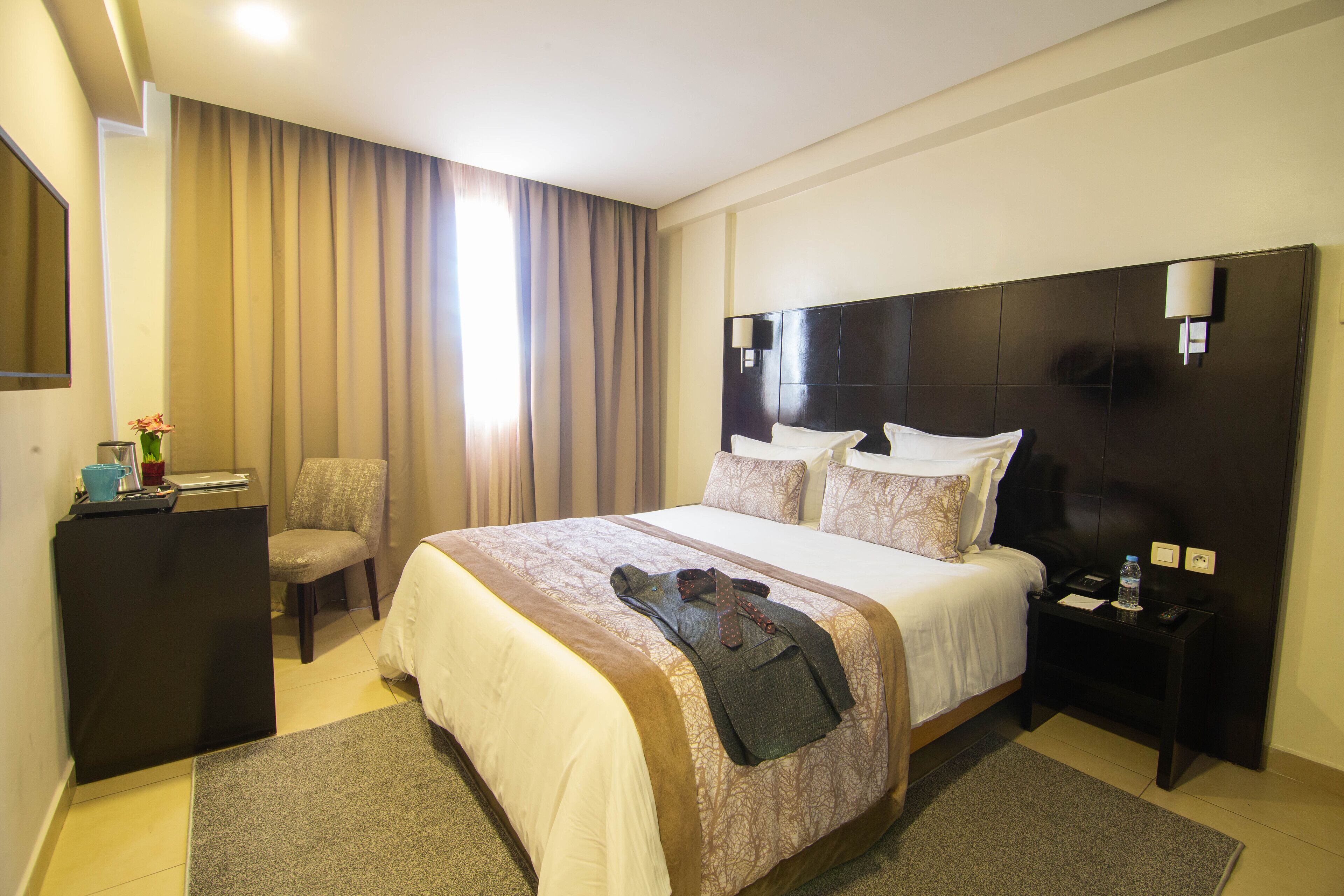 Een hotelkamer met een groot bed, een bureau, een stoel en een nachtkastje.