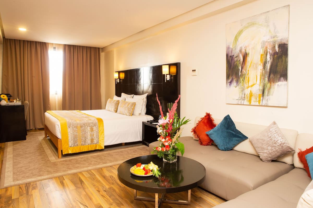 Una habitación de hotel con una cama doble, un sofá, una mesita de café y un cuadro en la pared.
