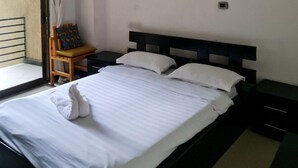 Un dormitorio con cama, una silla, un almohadón y dos adornos en la pared.
