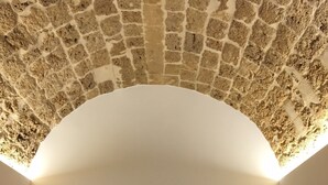 A bedroom with a stone ceiling, a bed with a metal frame, and two bedside lamps. - B&B Macrina (Noto)