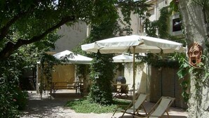 An outdoor patio area with white umbrellas, lounge chairs, and a grill. - B&B Macrina (Noto)