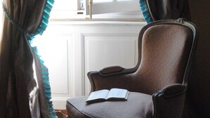 A chair with an open book, positioned near a window with curtains. - Hotel Particulier Le Ragois (Richelieu)