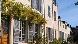 A building with multiple windows and shutters, a gravel courtyard, and potted plants. - Hotel Particulier Le Ragois (Richelieu)