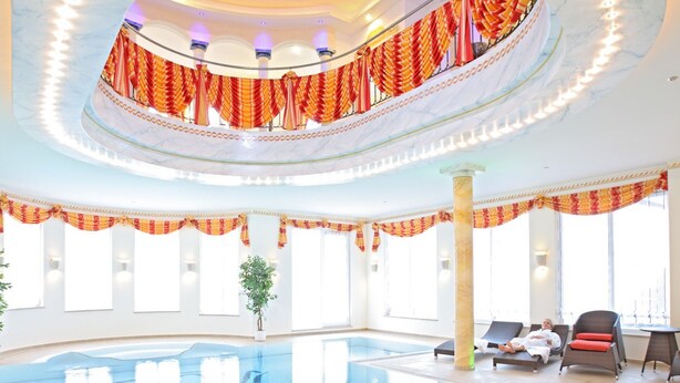 An indoor swimming pool with a circular ceiling, large windows, and sun loungers. - Wellness Privathotel Post an der Therme (Badenweiler)