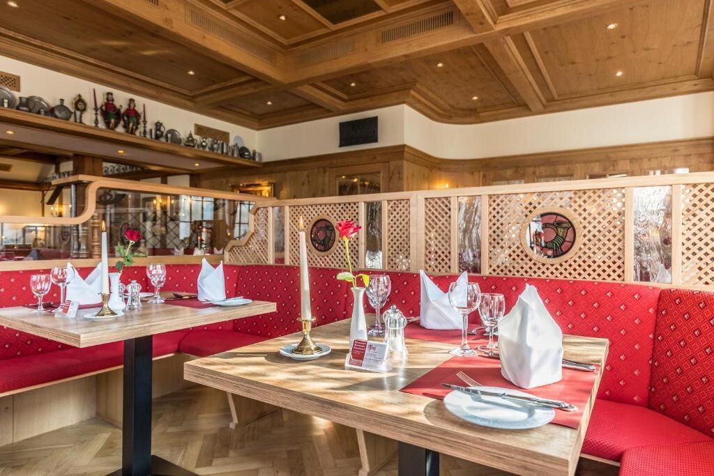 Ein Restaurantinneres mit Holztischen und roten Sitzbänken.