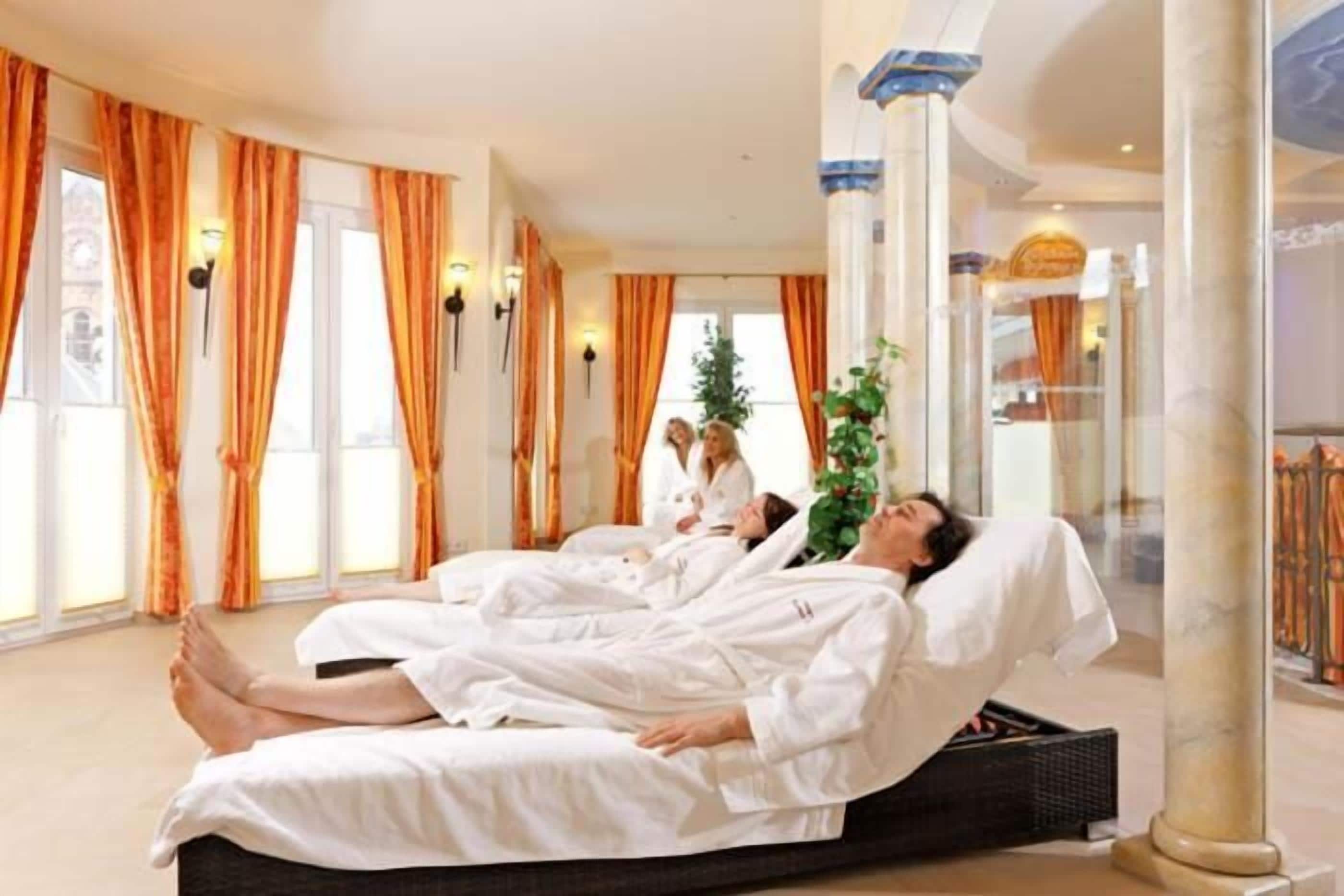 A hotel room with a bed, a window with curtains, and a plant.