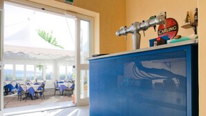 Habitación de hotel con un mueble azul, una grifería de cerveza Carling y vistas a un patio exterior con mesas y sillas.