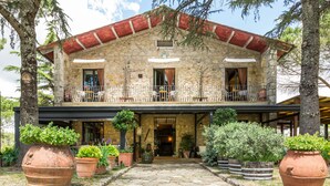 A stone building with a balcony, potted plants, and a stone pathway leading to the entrance. - Villa Di Capovento (Radda in Chianti)