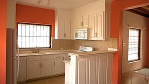 A kitchen with white cabinets, a microwave, and a dishwasher. - Trilogy Villas (Falmouth Harbour)