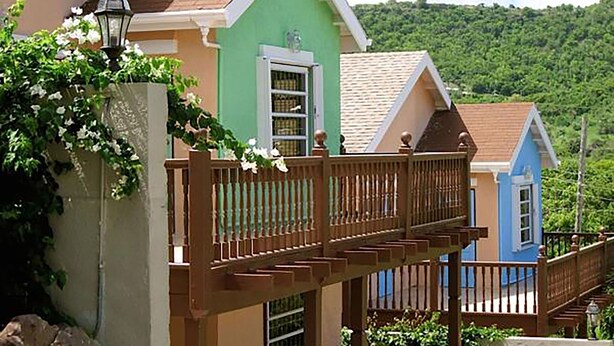 A row of colorful houses with a wooden bridge connecting them. - Trilogy Villas (Falmouth Harbour)